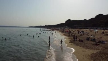 İnsanlar İngiltere 'nin Bournemouth kumlu plajında, güzel Britanya Deniz Manzarası ve Büyük Britanya' nın Temiz Okyanusu 'nda eğleniyor ve dinleniyorlar.
