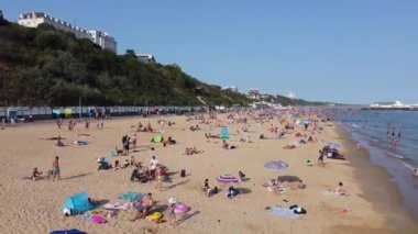People are Enjoying and relaxing at Bournemouth Beach of England UK, The Footage taken at Bournemouth Beach on the Hottest Summer Day. The Sea view was full of people, most of them was swimming in the ocean water, 