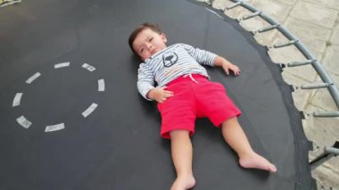 Baby Boy, Drone 'un kamerasının altında, bahçede trambolinde poz veriyor.