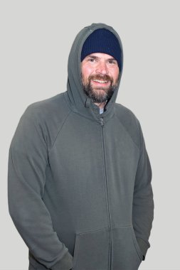 Mavi bereli ve yeşil kapüşonlu terli orta yaşlı bir adam. Soğuk sonbahar havasına hazırlanıyorum..