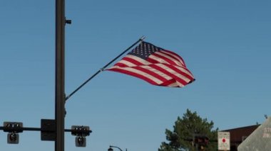 American flag blowing in the wind along a busy city street in Olathe Kansas