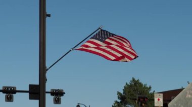 American flag blowing in the wind along a busy city street in Olathe Kansas