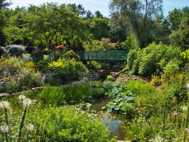 Green bridge in the middle of a flower garden in Overland Park Kansas on a hot sunny Summer day.