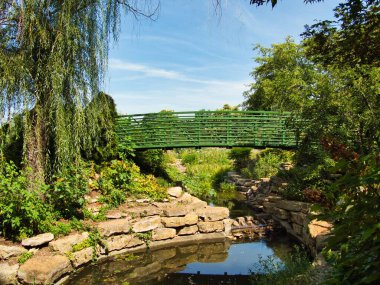 Green bridge in the middle of a flower garden in Overland Park Kansas on a hot sunny Summer day.