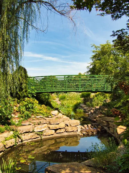 Green bridge in the middle of a flower garden in Overland Park Kansas on a hot sunny Summer day.