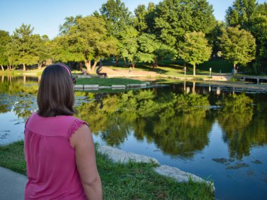 Brunette standing by the reflective waters of Sar Ko Par Park in Lenexa Kansas