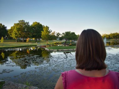 Brunette standing by the reflective waters of Sar Ko Par Park in Lenexa Kansas