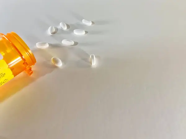 Prescription pills spilled onto an all white surface - White background with plenty of copy space