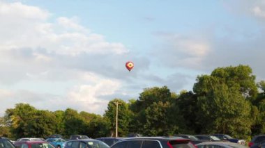 Colorful hot air balloon taking flight near a crowded parking lot in Lawrence Kansas