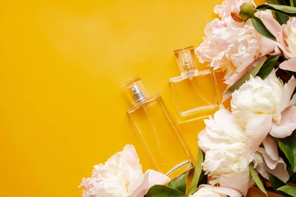 perfume bottles with with peonies on orange table