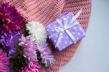 asters on knitted pink sweater with present box. gift and flowers