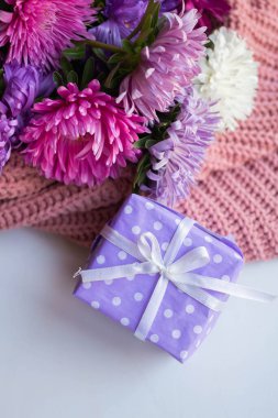 asters on knitted pink sweater with present box. gift and flowers