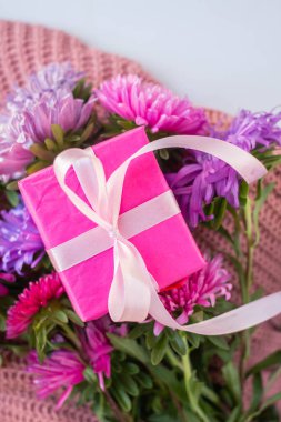 asters on knitted pink sweater with present box. gift and flowers