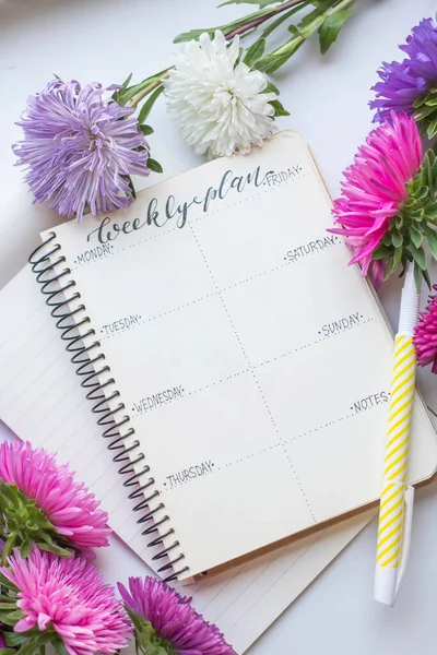 Weekly planner with asters, tea and autumn flowers.
