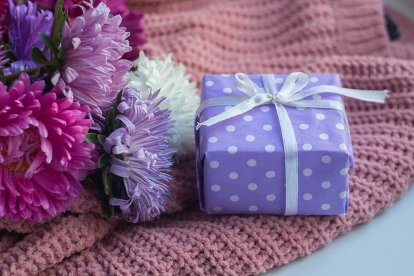asters on knitted pink sweater with present box. gift and flowers