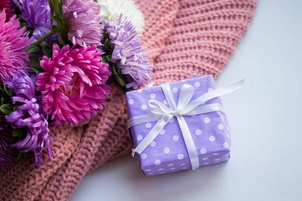 asters on knitted pink sweater with present box. gift and flowers