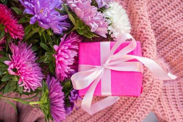 asters on knitted pink sweater with present box. gift and flowers