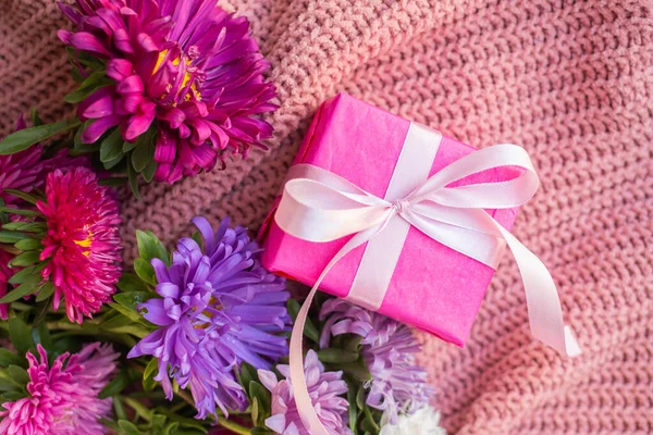 asters on knitted pink sweater with present box. gift and flowers