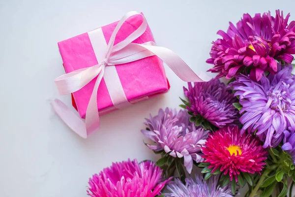 asters on knitted pink sweater with present box. gift and flowers
