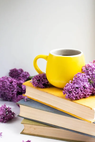 cup with cofee with lilac flowers and books. mug and lilac