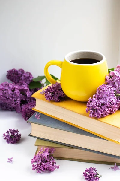 cup with cofee with lilac flowers and books. mug and lilac