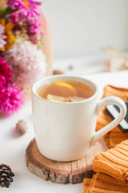 cup of tea with lemon. flowers and yelow sweater