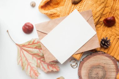 fall mockup card with autumn leaves invitation card with environment and details Mockup with postcard and sweater with wood elemets on white background.