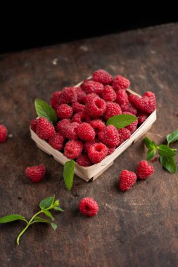 fresh raspberry in basket on dark wooden background