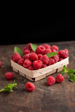 fresh raspberry in basket on dark wooden background
