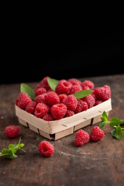 fresh raspberry in basket on dark wooden background