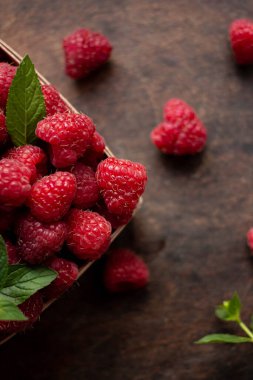 fresh raspberry in basket on dark wooden background