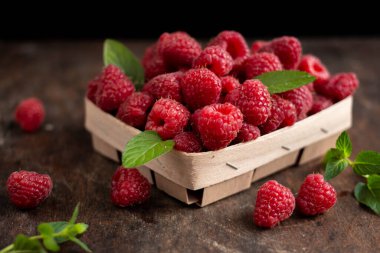 fresh raspberry in basket on dark wooden background