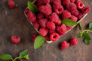 fresh raspberry in basket on dark wooden background