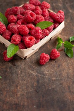 fresh raspberry in basket on dark wooden background