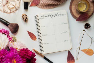 weekly planner with asters and candle. autumn leaves and flowers