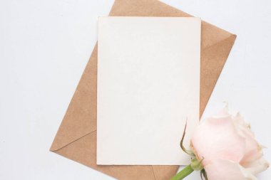 Minimalistic card mockup with roses. craft envelope, white flowers, branches, flat lay, top view. wedding invitation
