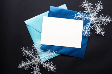 Kart maketi davetiyesi. Gümüş renkli ağaç topları ve parıldayan yıldızlarla siyah zemin üzerinde kar taneleri. Noel zamanı. yeni yıl 