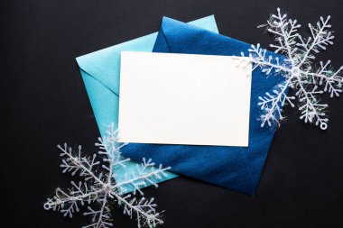 Kart maketi davetiyesi. Gümüş renkli ağaç topları ve parıldayan yıldızlarla siyah zemin üzerinde kar taneleri. Noel zamanı. yeni yıl 