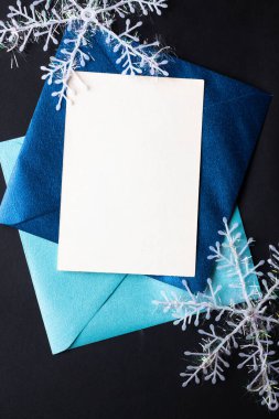 Kart maketi davetiyesi. Gümüş renkli ağaç topları ve parıldayan yıldızlarla siyah zemin üzerinde kar taneleri. Noel zamanı. yeni yıl 