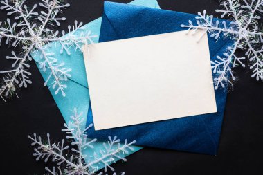 Kart maketi davetiyesi. Gümüş renkli ağaç topları ve parıldayan yıldızlarla siyah zemin üzerinde kar taneleri. Noel zamanı. yeni yıl 