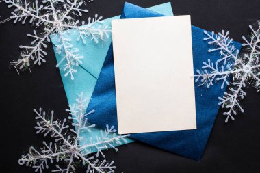 Kart maketi davetiyesi. Gümüş renkli ağaç topları ve parıldayan yıldızlarla siyah zemin üzerinde kar taneleri. Noel zamanı. yeni yıl 