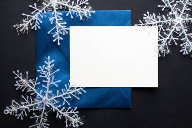 Kart maketi davetiyesi. Gümüş renkli ağaç topları ve parıldayan yıldızlarla siyah zemin üzerinde kar taneleri. Noel zamanı. yeni yıl 
