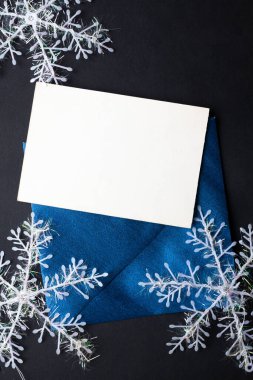 Kart maketi davetiyesi. Gümüş renkli ağaç topları ve parıldayan yıldızlarla siyah zemin üzerinde kar taneleri. Noel zamanı. yeni yıl 