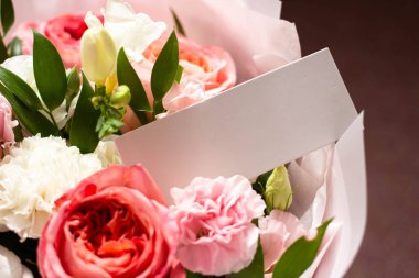 Bir buket çiçek ve gönderenden bir kart. Bilinmeyen bir hayran. Güller, karanfiller, lisianthus. Kart modeli