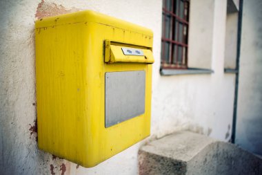 Duvarda parlak sarı bir posta kutusu var. Yaklaş..