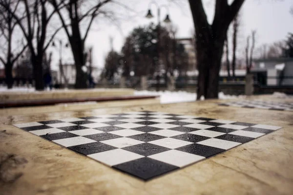 Outdoor chess stone table on a cold winter day, close up.