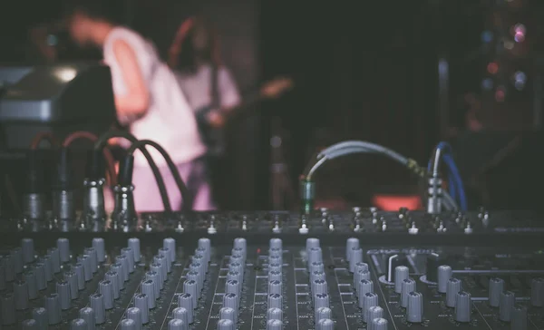 Audio mixer and music equipment during a live show, bokeh blurred background.