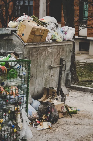 Çöp konteynırının çöplerle dolup taşması, dikey görüntü. Çevre ve ekoloji sorunu, arazi kirliliği ve plastik atık kavramı.