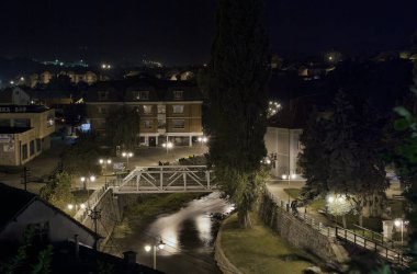 Sırbistan 'ın doğusundaki Knjazevac şehrinin eski merkezi. Timok nehri üzerindeki metal köprü, gezinti güvertesi olan küçük bir park. Gece fotoğrafçılığı, uzun pozlama. 