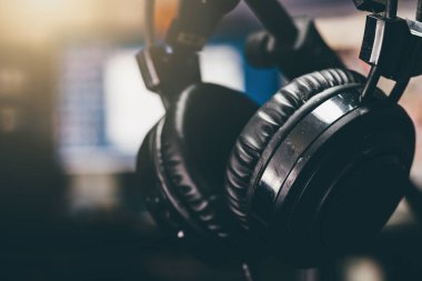 Black used headphones on a stand in a studio. Selective focus, blurred background, close up.